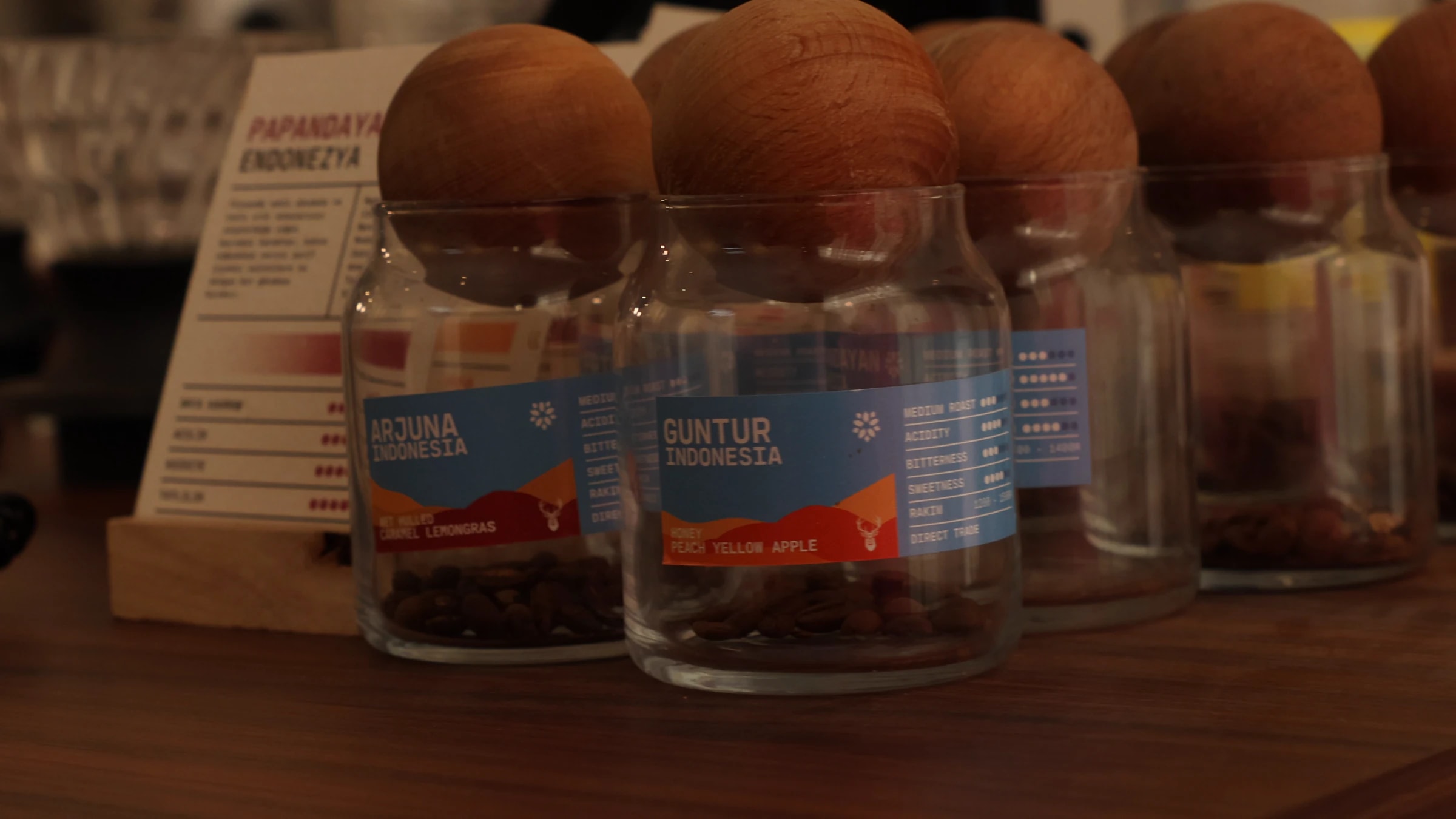 Coffee Bar tezgâhında Arjuna, Guntur ve Papandayan çekirdek kavanozları ve tadım kartı
